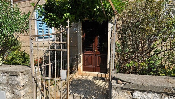 Une entrée en pierre avec un portail en métal, une porte en bois et un mur en pierre.