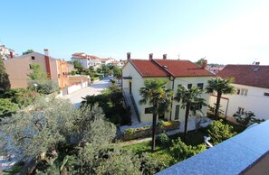 A residential area with a house featuring a red-tiled roof, a staircase, and a small garden with palm trees. - SENA Studio with Balcony 2 (Rovinj)
