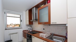 A compact kitchen with a window, a built-in stove, a sink, and cabinets. - TANJA Studio with Balcony (Rovinj)