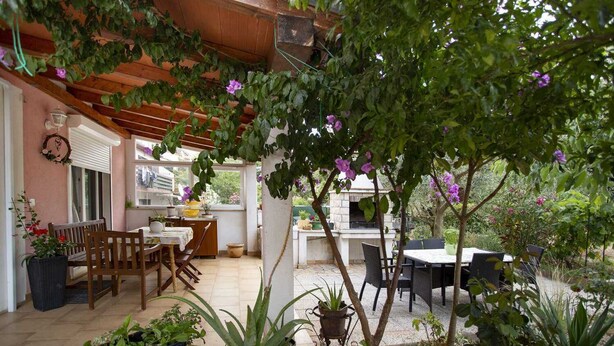 A covered patio area with outdoor seating, a stone fireplace, and potted plants. - ULIKA Studio Apartment 1 (Rovinj)