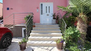 A building with a pink facade, a white door, and a staircase leading to the entrance. - ULIKA Studio Apartment 1 (Rovinj)
