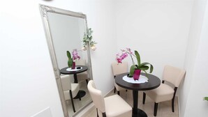 A corner room with a large mirror, two round tables with chairs, and potted orchids. - ULIKA Studio Apartment 1 (Rovinj)