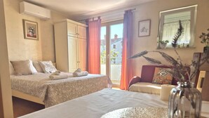A hotel room with two beds, a dining table with a vase, and a view of the outside. - ULIKA Studio Apartment 1 (Rovinj)