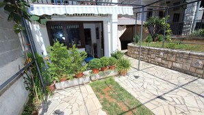 Une cour avec une terrasse en pierre, des plantes en pot et un petit jardin.