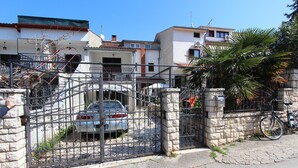 Un lotissement résidentiel fermé, avec une voiture garée, des murs en pierre et un vélo.