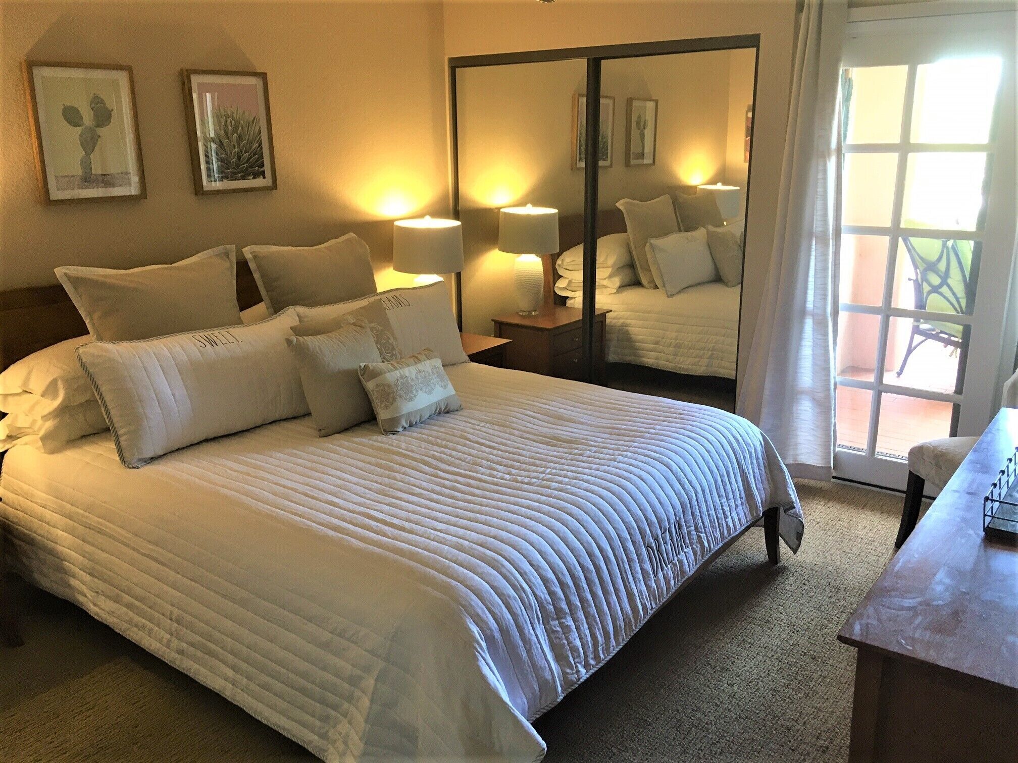 A neatly made bed with a quilted cover, multiple pillows, and bedside lamps.