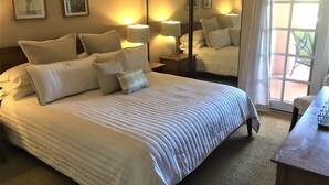 A neatly made bed with a quilted cover, multiple pillows, and bedside lamps.