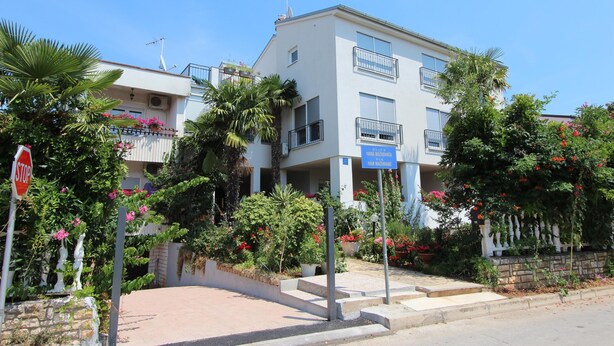 A two-story residential building with balconies, surrounded by lush greenery and flowering plants. - SALLY Comfort Studio 6 (Rovinj)