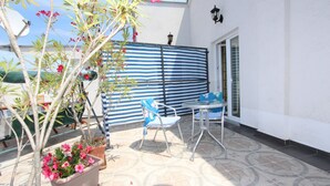 A patio with a striped fence, a table, a chair, and potted plants. - SALLY Comfort Studio 6 (Rovinj)