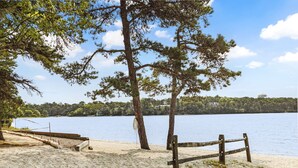 Une plage de sable avec une clôture en bois et des arbres.