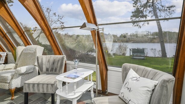 Une pièce confortable avec vue sur un lac, comprenant un canapé, un fauteuil et une petite table sur laquelle est posé un magazine.