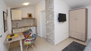Un espacio habitable compacto con kitchenette, comedor, televisor montado en la pared y armario.