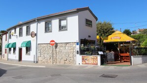 Un edificio con restaurante llamado "Ozulisko Pizza-Grill" en la planta baja, con fachada de piedra y techo de tejas rojas.