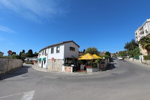 A street corner with a white building, a yellow umbrella, and a sign that reads "Café".