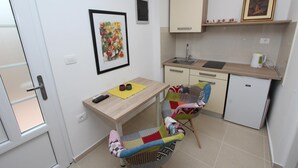 Una cocina compacta con fregadero, un refrigerador pequeño y una zona de comedor con una silla y mesa.
