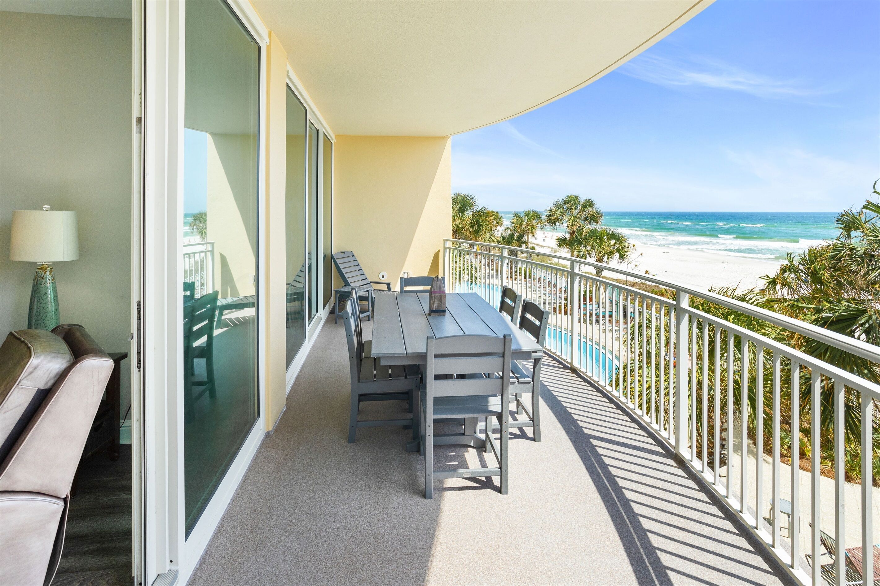 Ein Balkon mit Tisch und Stühlen, einer Sitzecke und Blick auf Strand und Meer.