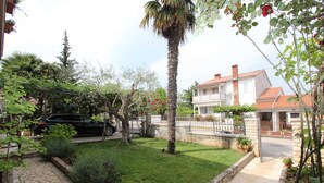 A residential property with a well-maintained lawn, a stone pathway, and a two-story house with a red-tiled roof.