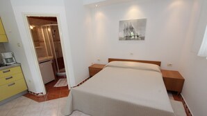 A bedroom with a bed, bedside tables, a painting, and a bathroom with a shower.