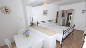 Un dormitorio con cama, escritorio, silla y una pequeña mesa con un florero.