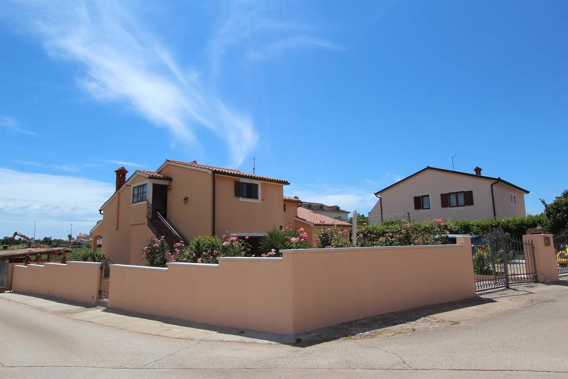 A residential area with two houses, one with a visible staircase and a small garden with pink flowers.