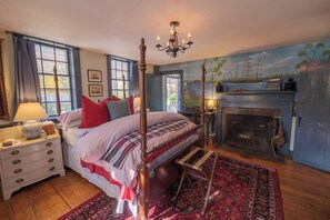 A bedroom with a four-poster bed, a fireplace, and a mural on the wall. - 1784 Denison Home~ New England Nautical Inspiration~ Welcome to Warm Hospitality (Stonington)