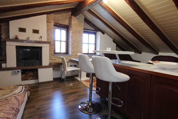 A cozy kitchen with a fireplace, wooden beams, and a dining area with bar stools.