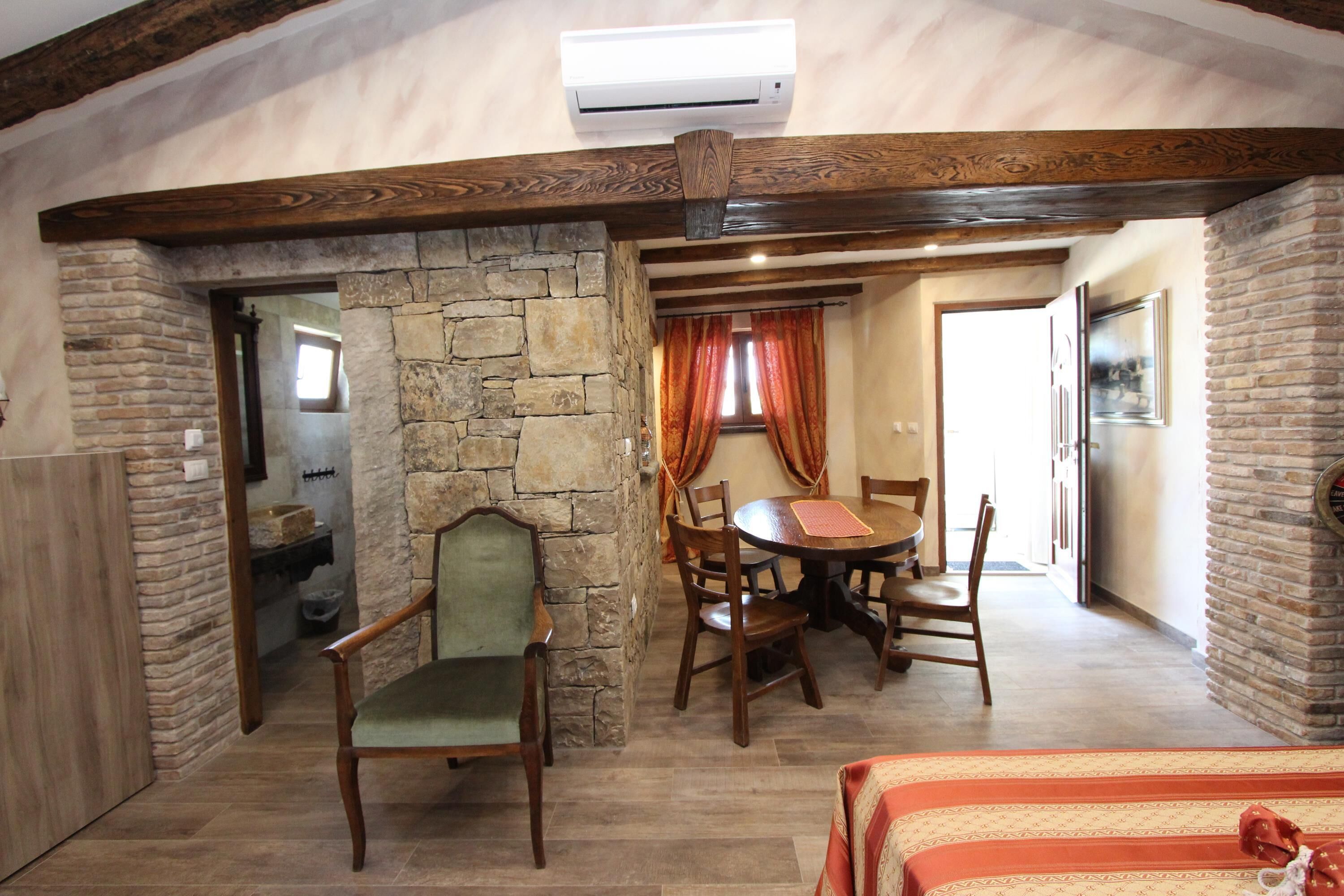 A dining area with a stone wall, wooden furniture, and a view into another room.
