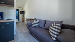 A modern living room with a sofa, a coffee table, and a dining area. - DOMIC Studio Apartment 1 (Banjole)