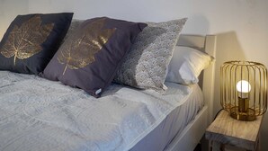 A bed with patterned pillows, a bedside table with a lamp, and a plain wall. - DOMIC Studio Apartment 1 (Banjole)