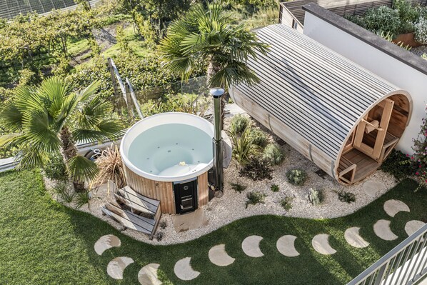 Un bain à remous, une terrasse en bois et une petite construction en bois dans un jardin aménagé.