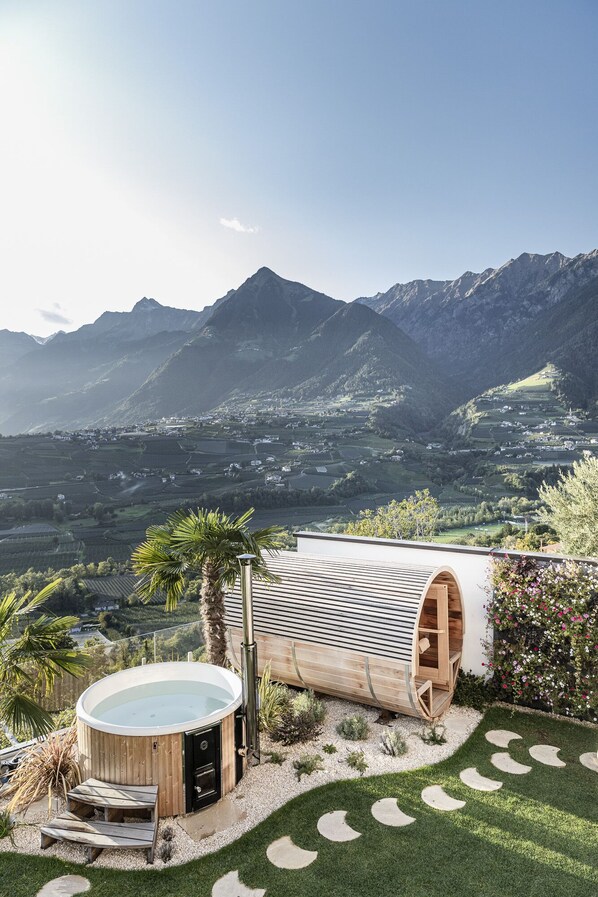 A modern outdoor hot tub area with a view of mountains and vineyards.