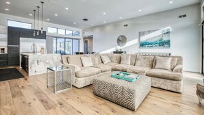 A spacious living area with a large sectional sofa, a coffee table, and a modern kitchen in the background. - Scottsdale Walk to Old Town - 4BR Luxury Villa w/ Pool, Spa & Fire Pit (Scottsdale)