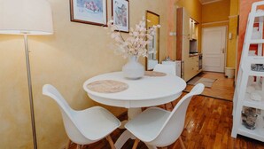 A dining area with a round table, white chairs, a vase with flowers, and framed pictures on the wall. - VILLA ROSSELLA 2 Studio (Eufemia) (Rovinj)