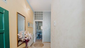 A hallway with a green door, a mirror, framed pictures, and a vase with flowers on a small table. - VILLA ROSSELLA 2 Studio (Cardaria) (Rovinj)