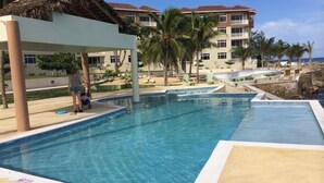 Ein Swimmingpool mit klarem, blauem Wasser, umgeben von einer Liegefläche mit Stühlen und einer Palme.