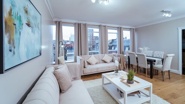 Een moderne woonkamer met een bank, salontafel, eettafel en stoelen.