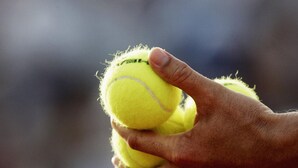 Een hand die twee tennisballen vasthoudt.
