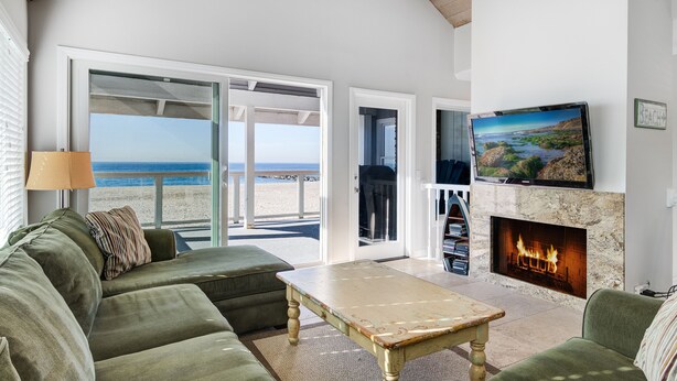 A living room with a green sofa, a wooden coffee table, a fireplace, and a large TV.