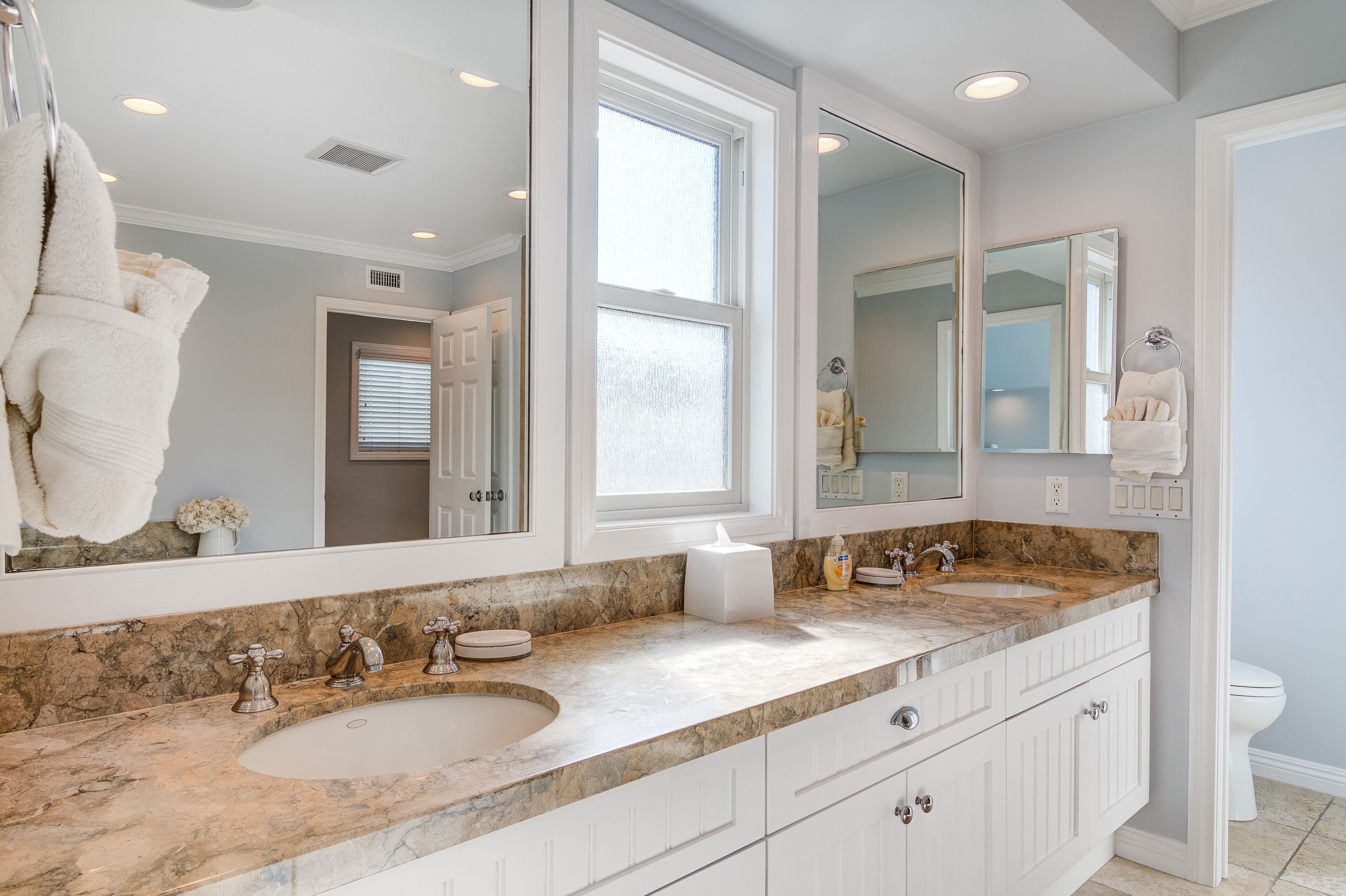A bathroom with a large mirror, a sink, and a toilet.