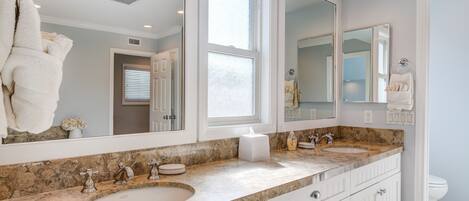 A bathroom with a large mirror, a sink, and a toilet.