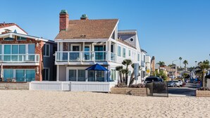 A beachfront property with a two-story house, a balcony, and a beach view.