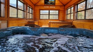 A wooden cabin with a hot tub, large windows, and a television. - 3bd/4ba on Acre/Indoor Heated Pool/ Theater/Hot Tub/Billiards/Wifi/FirePit/Hike (Cosby)