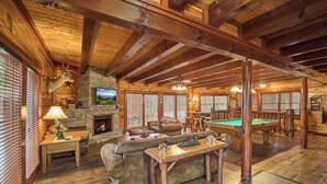 A spacious lodge with a pool table, comfortable seating, a fireplace, and a stone wall. - 3bd/4ba on Acre/Indoor Heated Pool/ Theater/Hot Tub/Billiards/Wifi/FirePit/Hike (Cosby)