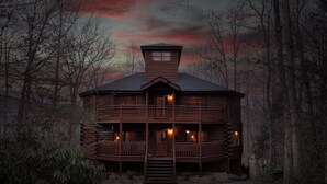 A wooden log cabin with a central tower, multiple balconies, and a porch with lights. - 3bd/4ba on Acre/Indoor Heated Pool/ Theater/Hot Tub/Billiards/Wifi/FirePit/Hike (Cosby)