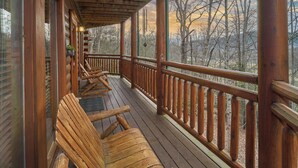 A wooden deck with benches, a railing, and a view of trees. - 3bd/4ba on Acre/Indoor Heated Pool/ Theater/Hot Tub/Billiards/Wifi/FirePit/Hike (Cosby)