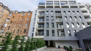 A modern apartment building with multiple balconies, a courtyard, and surrounding greenery. - Stylish Apartment with Parking | Air Conditioning | Near the Market Square (Poznań)