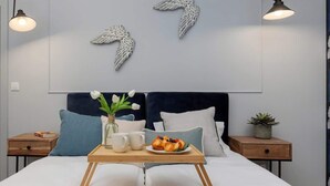 A neatly made bed with a tray of pastries and coffee cups, a vase with flowers, and decorative wall art. - Stylish Apartment with Parking | Air Conditioning | Near the Market Square (Poznań)