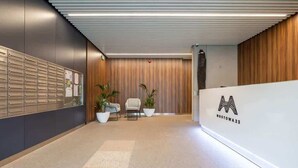 A modern reception area with a wooden panel wall, a metal filing cabinet, two white chairs, and potted plants. - Stylish Apartment with Parking | Air Conditioning | Near the Market Square (Poznań)