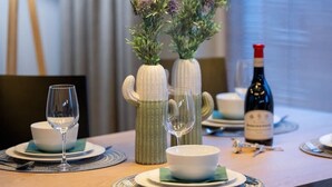 A dining table set with plates, bowls, wine glasses, and a bottle of wine. - Elegant Apartment Near the Old Market Square | Parking (Poznań)
