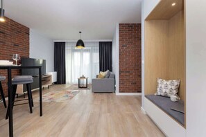 Un salon moderne avec un canapé, un coin repas comprenant une table et des chaises, un téléviseur et un mur d’accent en briques.